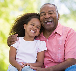 A grandfather and granddaughter smiling. Links to Gifts That Protect Your Assets